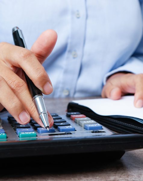 Closeup of marketing expert using calculator. Person working with document at desk. Marketing concept. Cropped view.